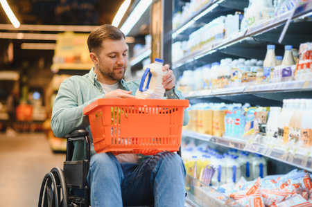 Man in a wheelchair shopping for groceries at a supermarket, placing a milk bottle into his shopping basket with confidence and easeの写真素材