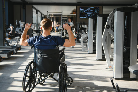 Patient lifting dumbbells during a rehabilitation workout in the gym, focusing on strength training and recovery while embracing determination and resilienceの写真素材