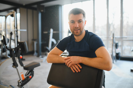 Smiling man resting after completing rehabilitation exercises in a modern gym, demonstrating...