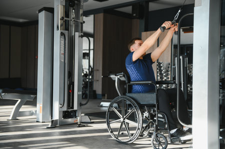 Man with disability in wheelchair using lat pulldown machine, showcasing accessible fitness and rehabilitation through exerciseの写真素材