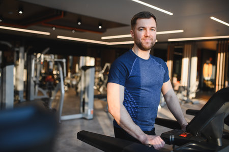 Bearded man engaging in rehabilitation exercises on a treadmill in a modern gym, focusing on fitness and recovery in an active environmentの写真素材