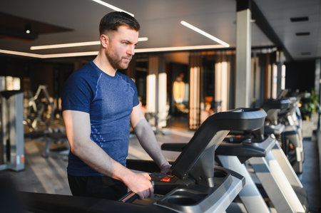 Focused male athlete exercising on treadmill in modern gym, concentrating on rehabilitation and recoveryの写真素材