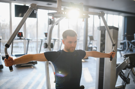 Patient exercising pectoral muscles with fitness equipment during physiotherapy session in...
