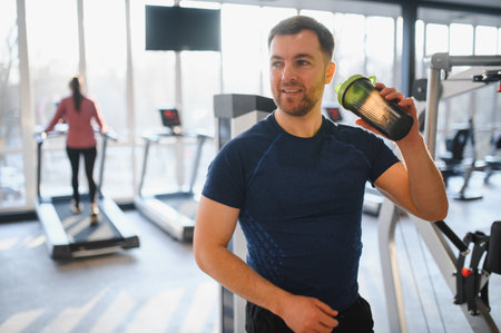 Patient enjoying a protein shake after completing an intense workout in a rehabilitation center gym, focusing on recovery and wellnessの写真素材