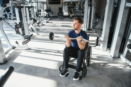 Man with disability exercising with barbell in modern gym, demonstrating strength and resilience during rehabilitation processの写真素材