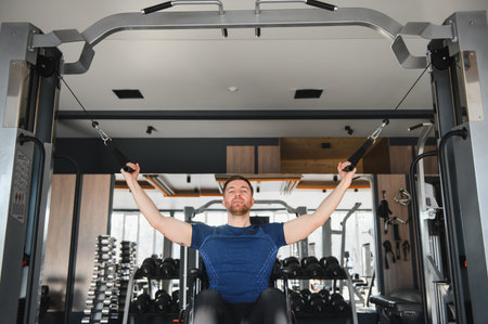Man in wheelchair exercising using cable machine in gym, demonstrating strength, resilience, and...