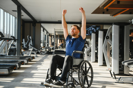 Man with disability exercise in wheelchair, lifting arms during rehabilitation workout in modern gym