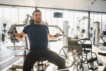 Person with disability using a chest press machine during rehabilitation workout in a bright gym
