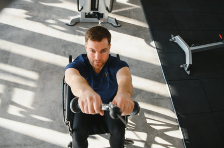 Determined man in wheelchair using cable row machine, demonstrating strength and resilience during...