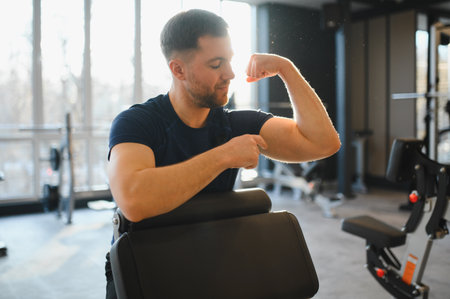 Man in a wheelchair confidently flexing bicep in a gym, highlighting strength and rehabilitation in...