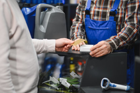 Customer making a contactless payment using credit card at a car parts store, assisted by the salesmanの写真素材