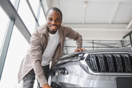 Smiling customer checking his new car in a dealership, touching the hood and examining the frontの写真素材