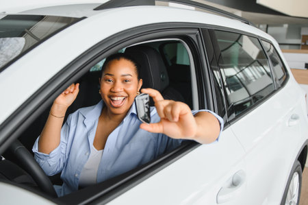 Happy customer displaying car keys while seated in a brand new vehicle within the showroom, radiating excitement and joyの写真素材