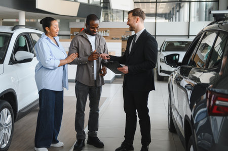Happy couple receiving car keys from a salesman in a car dealership, finalizing their purchase