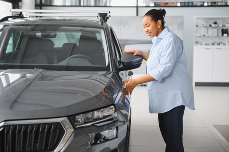 Pregnant african american woman checking a new gray suv crossover car in a car dealership showroom