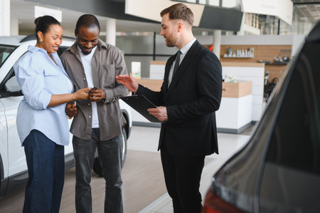 Car salesman explaining a contract to a young African American couple buying a new car in a dealershipの写真素材