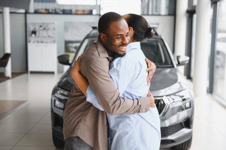 Excited couple embracing at a car dealership after purchasing their new car, celebrating a major milestoneの写真素材