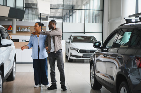 African american couple examining automobiles, discussing features and making decision about buying...