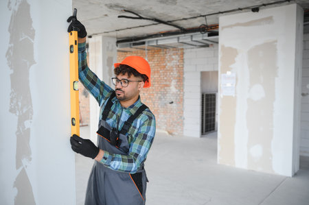 Focused engineer meticulously uses a spirit level, ensuring precise vertical alignment of a wall...