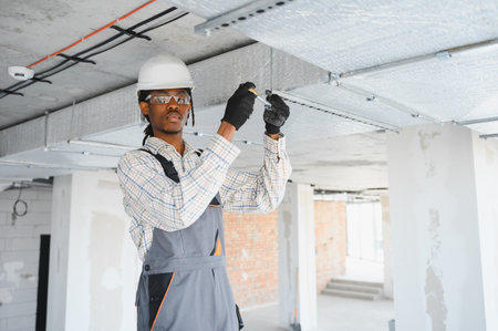 African american construction worker installing a ventilation system on a busy construction site,...