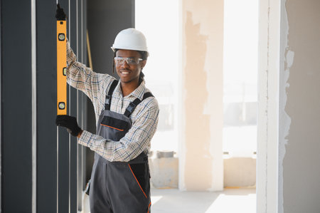 Smiling african american construction worker using spirit level while working on a construction site