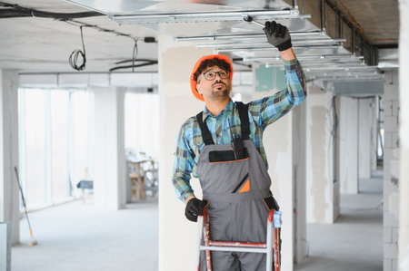 Arab engineer installing ceiling structure in a building construction site, working on a ladder and...