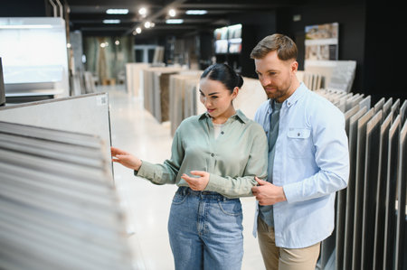 Young couple selecting ceramic tiles for their apartment renovation in a modern hardware storeの写真素材