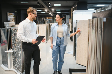 Shop assistant advising customer choosing ceramic tiles in a modern showroom of a building materials storeの写真素材