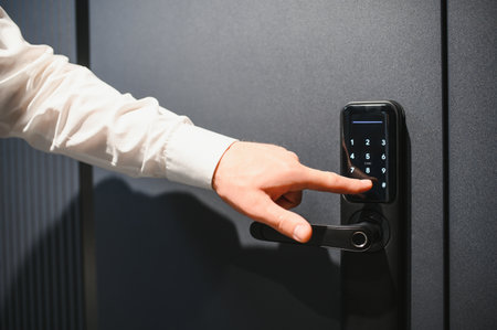 Hand entering security pin on electronic lock to open or close office, hotel, or apartment door