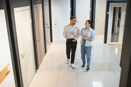 Female customer and male salesman discussing options in a ceramic tile and plumbing store,...