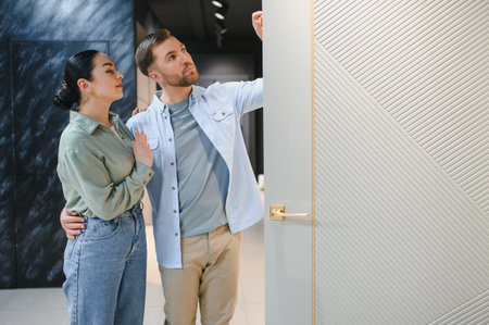 Couple selecting modern design door in a home improvement store, shopping for renovation materialsの写真素材
