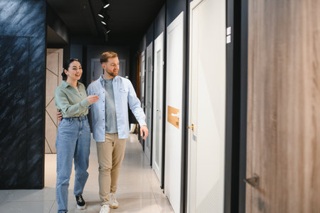 Happy couple walking through a hardware store, selecting interior doors for their new apartment and enjoying the home renovation journey togetherの写真素材