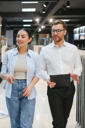 Female buyer and male seller engaging in conversation at a ceramic tile and plumbing store, showcasing customer service and product guidanceの写真素材