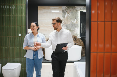Shop assistant showing different tiling options to customer in a plumbing store, discussing characteristics and pricesの写真素材