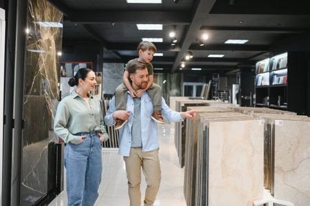 Happy family selecting ceramic tiles for their apartment renovation while enjoying time together in a modern hardware storeの写真素材