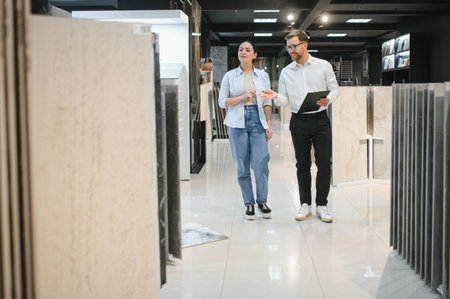 Salesman showing different types of ceramic tiles to a customer in a modern plumbing and tile store