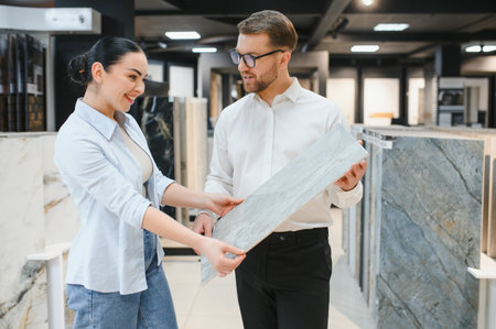 Shop assistant presenting a ceramic tile sample to a customer in a vibrant ceramic and plumbing store, enhancing the shopping experienceの写真素材