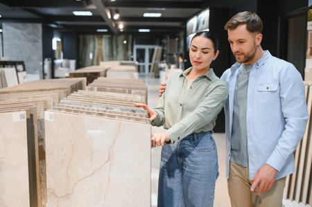 Couple selecting ceramic tiles for their apartment renovation while browsing a modern hardware store filled with design options and stylesの写真素材