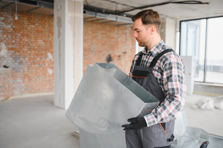 Hvac technician carrying metal air duct for ventilation system installation in a building under constructionの写真素材