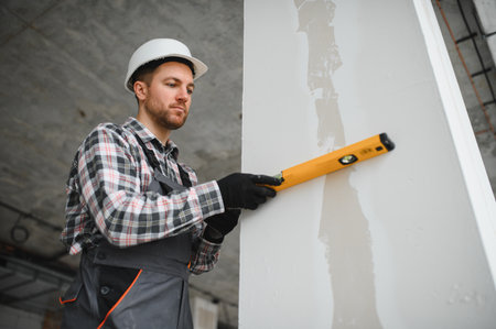 Builder using spirit level ensuring vertical alignment during building construction or renovationの写真素材