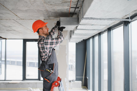 Builder with safety helmet installing an air conditioning system in a building under construction