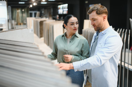 Couple selecting ceramic tiles in a hardware store, discussing options for their home renovation projectの写真素材