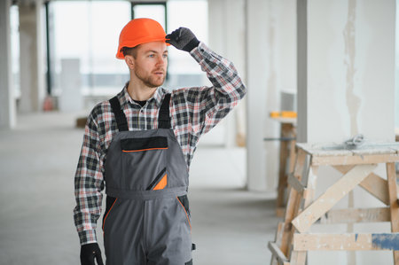 Construction worker adjusting his helmet while closely inspecting a building site, ensuring safety...