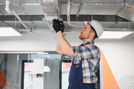 Builder wearing a safety helmet and using various tools while expertly installing an air...