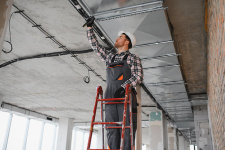 Builder with safety helmet installing ventilation pipes on a ladder in a building under construction