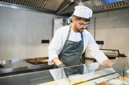Professional chef wearing black gloves and apron preparing a shawarma or kebab in a street food...