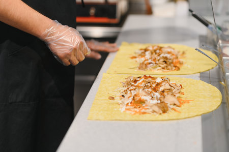 Cook adding ingredients to a shawarma or kebab in a fast food restaurant specialized in oriental...