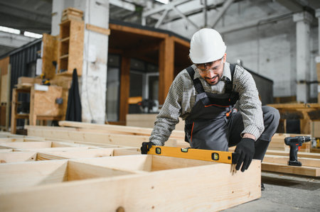 Skilled carpenter using spirit level ensuring precision in prefabricated house construction,...