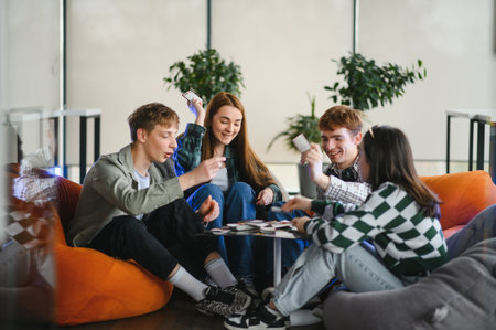 Four cheerful colleagues enjoying a break from work, playing a board game in a relaxed, modern...