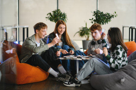 Four colleagues are sitting on beanbag chairs around a table, enjoying a board game during their...